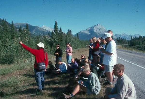 Students roadside, mountains in background listening to a lecture