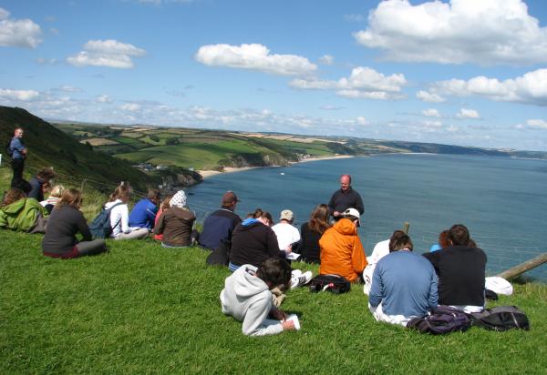 Students sitting hillside above water