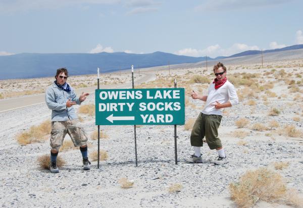 Two students standing on either side of a road sign for Owens Lake or Dirty Socks Yard