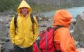 two students in rain gear walking along rocky coast