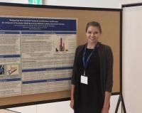 Alumni Larissa Goshulak standing beside her conference poster.