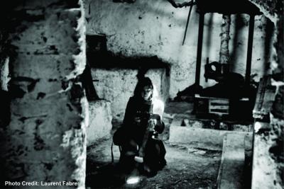 black and white photo of Karina kneeling down with her camera in an old stone building